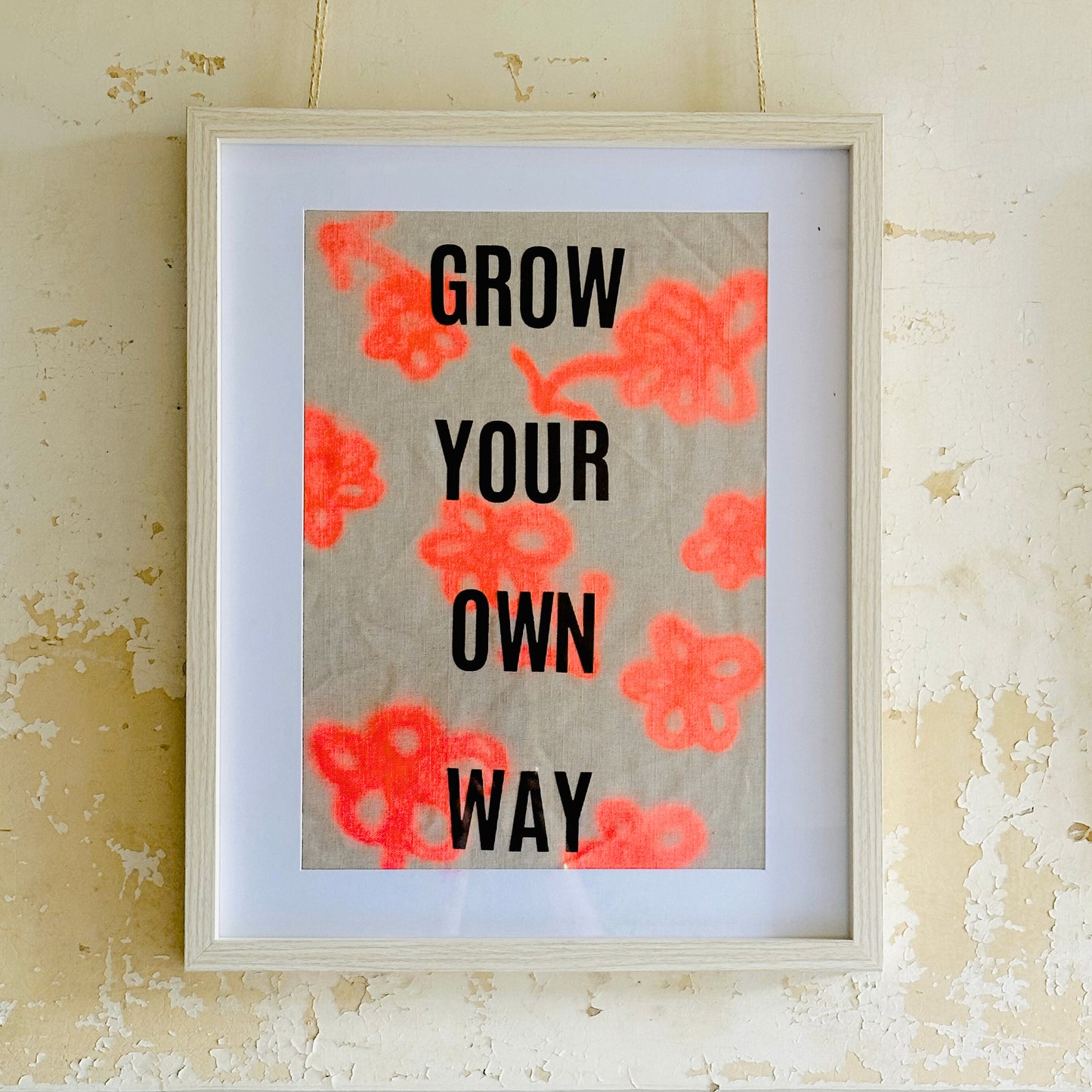 Framed print with motivational 'Grow Your Own Way' text on a linen fabric in neon orange