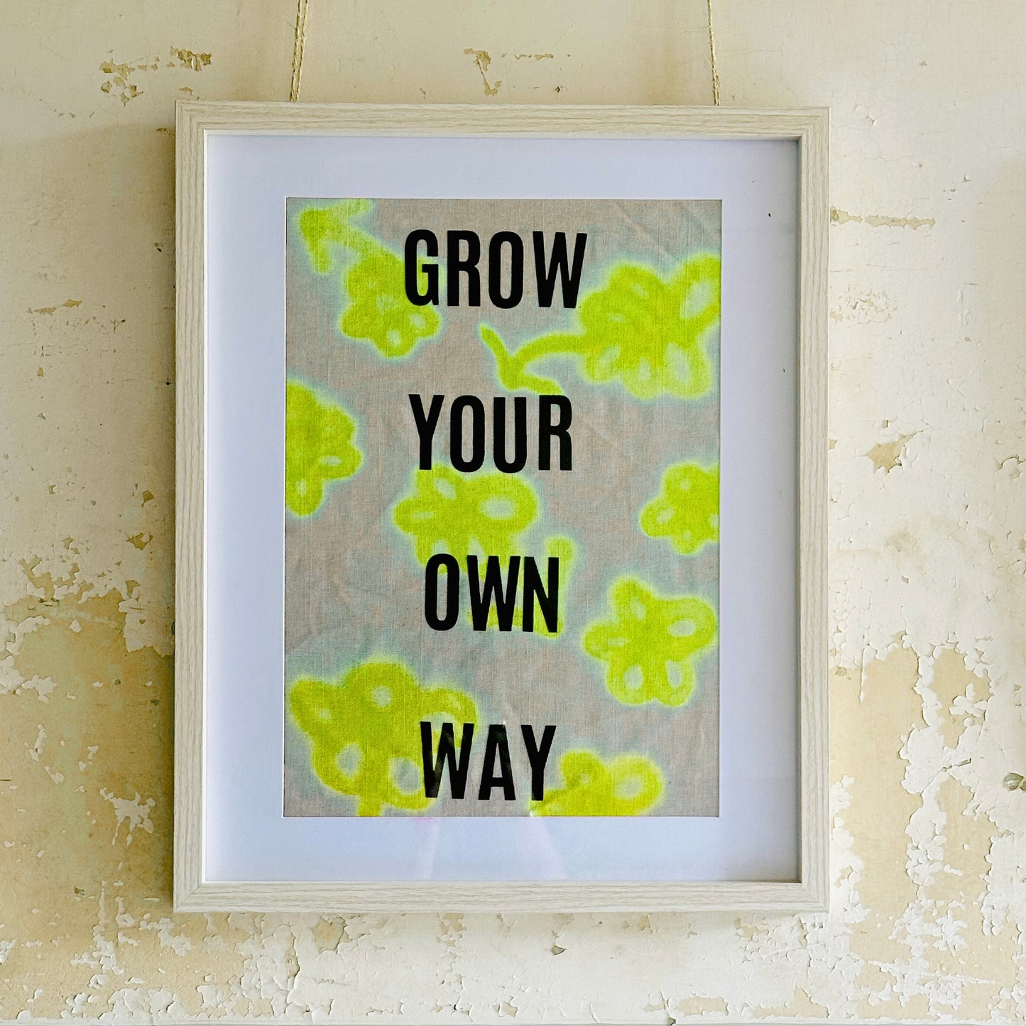Framed print with motivational 'Grow Your Own Way' text on a linen fabric in neon yellow flowers