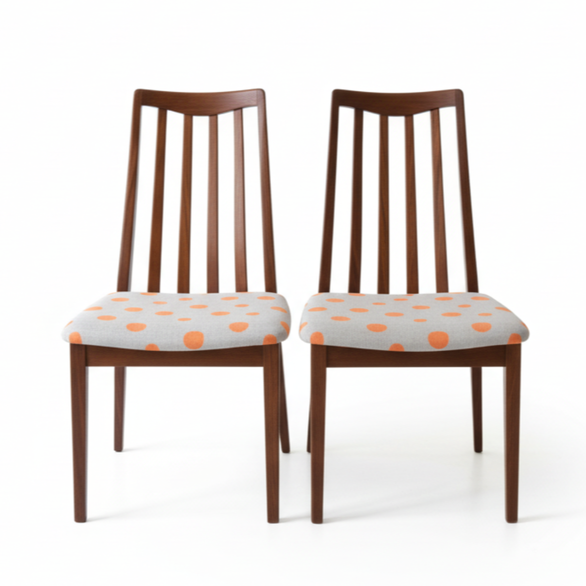 vintage g plan Two wooden chairs with polka dot cushions on a white background