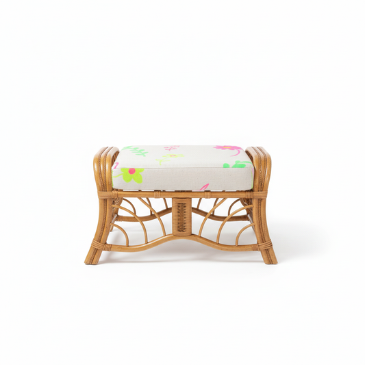 Wicker bamboo ottoman stool with a floral cushion on a white background