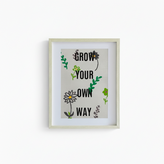 Framed artwork with motivational quote 'Grow Your Own Way' on a white background
