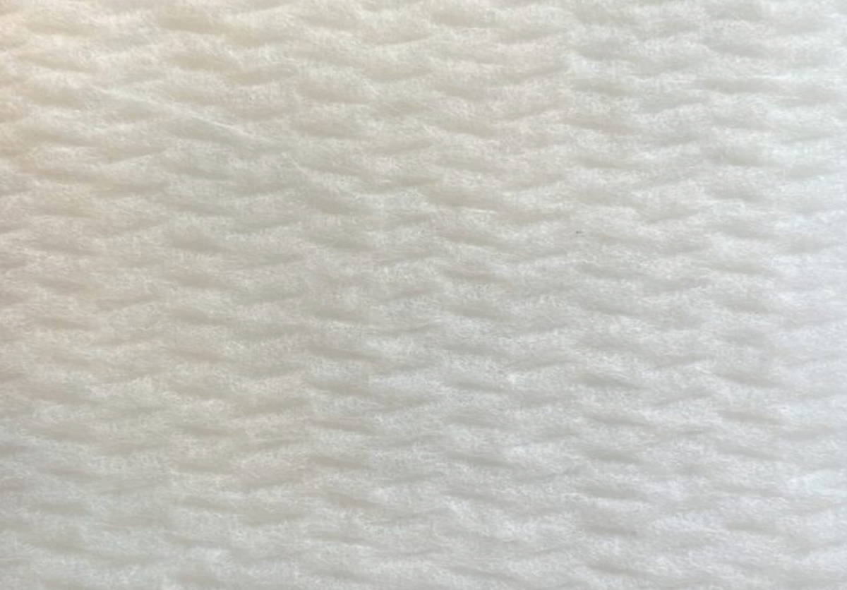 A close-up texture shot of a white, textured foam material with a wavy, ribbed pattern.